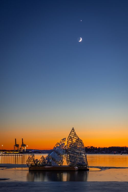 Free Serene view of Oslo Barcode Project at sunset with a crescent moon and vibrant sky. Stock Photo