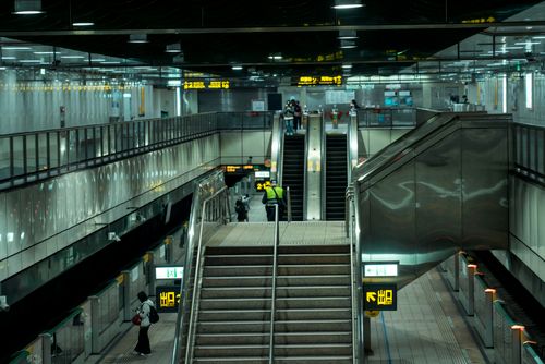 Free Busy Taipei metro station interior showing escalators and directional signs, capturing urban transit life. Stock Photo