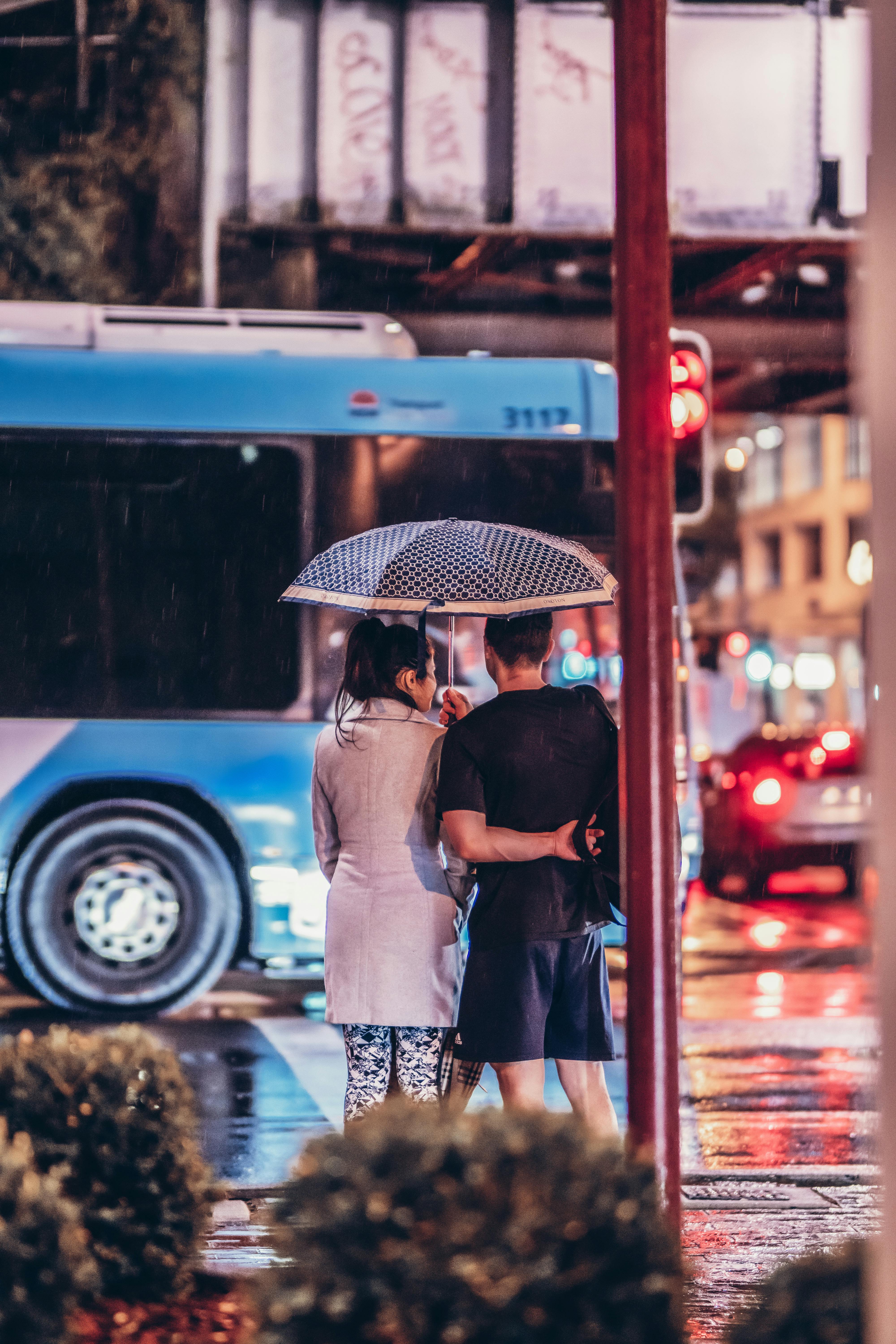 Intimate couple embracing closely under moody rainy night lighting, tender and sensual connection