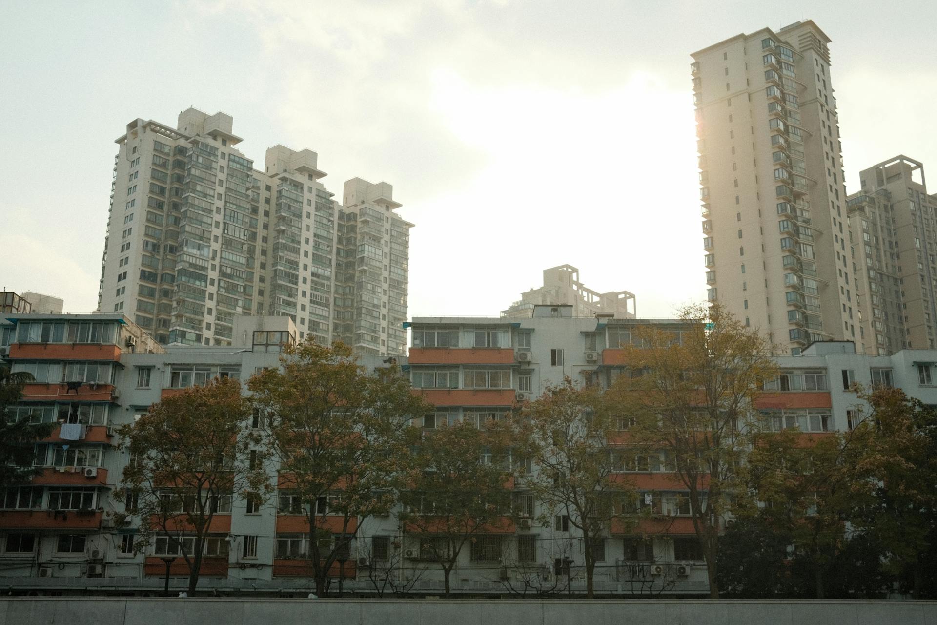 Tall residential buildings with sun setting behind create an urban skyline.