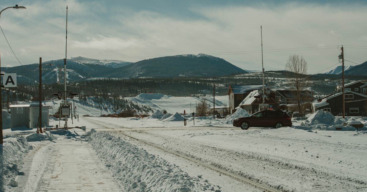 Capturing a tranquil snowy scene in a small Colorado town with mountains in the background.