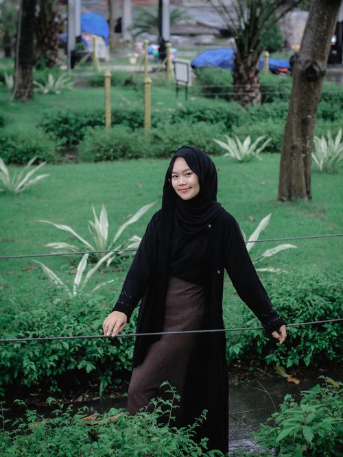 Free Portrait of a woman in a hijab standing in a green park, exuding tranquility. Stock Photo