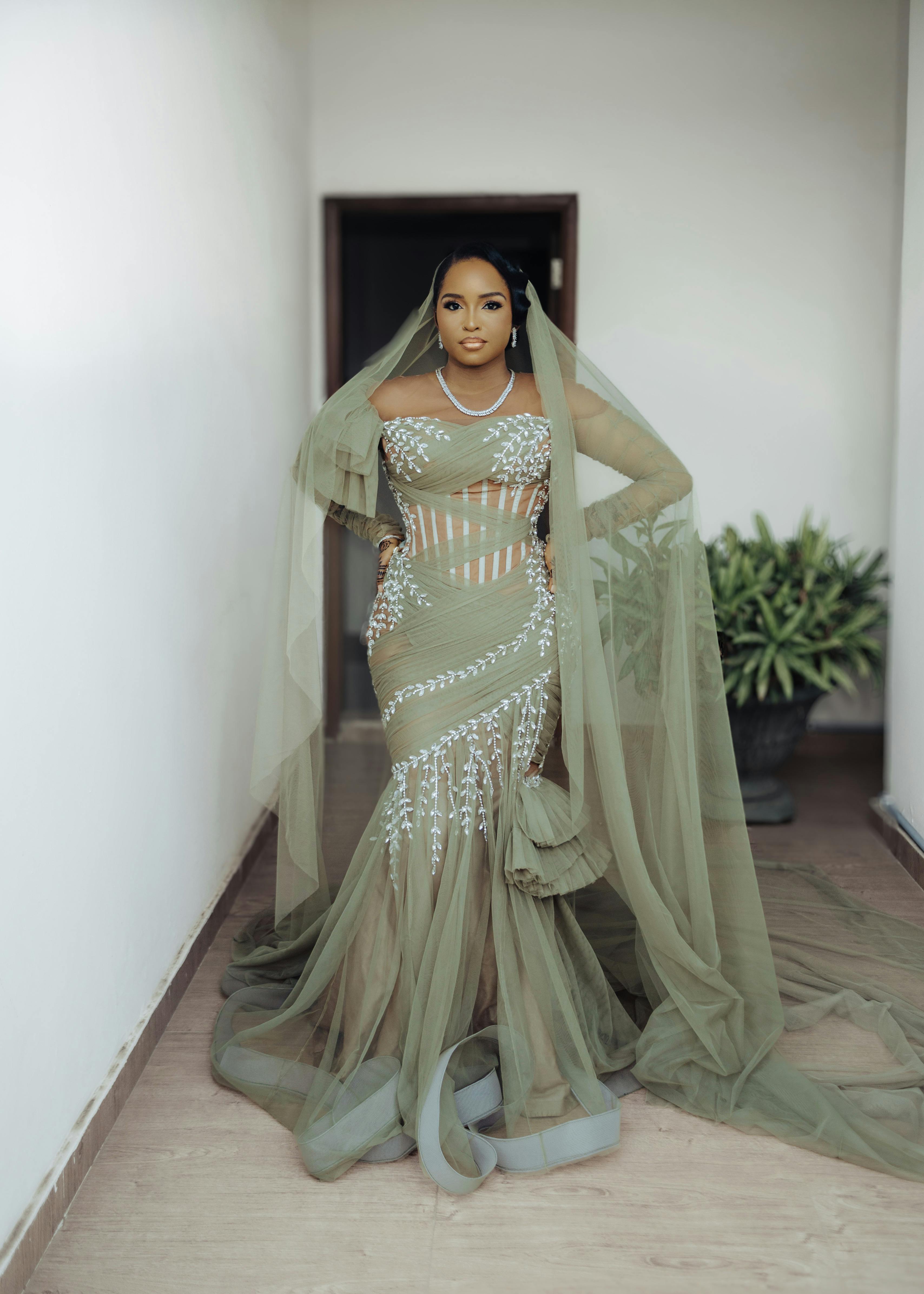Fashion portrait of a woman wearing an elegant green sheer gown indoors.