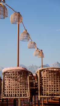 Charming outdoor cafe seating with woven chairs and mountain backdrop, ideal for travel imagery.