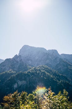 在晴朗的蓝天下，阳光明媚的山峰与壮丽的山脉景色，共同捕捉了白天的自然之美