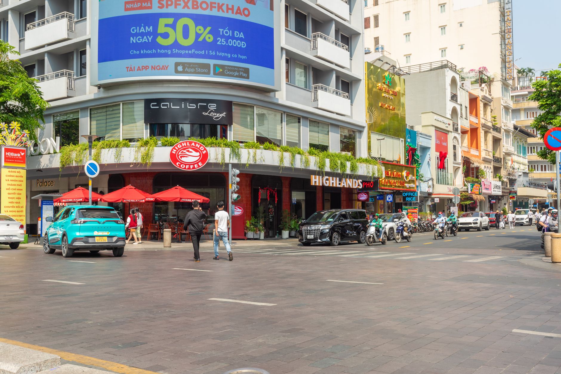 Busy street view of Hồ Chí Minh City with Highland Coffee and bustling traffic.