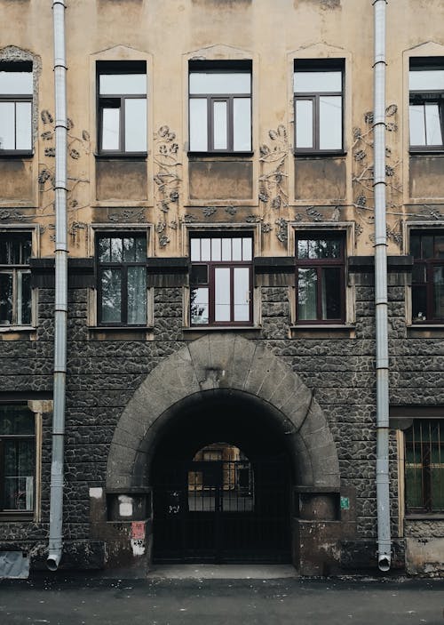 Exterior of aged weathered building with arch located on city street on gray day