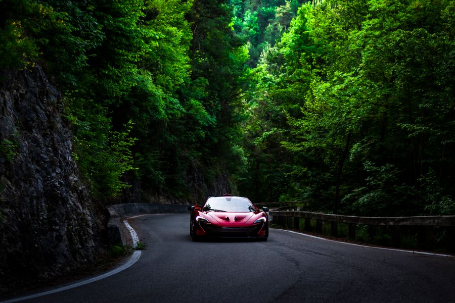 Red supercar pulling hard through the mid-range on a forest road