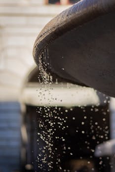 Artistic close-up of a water fountain with droplets falling against an architectural backdrop.