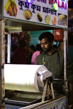 Street vendor making traditional rolled ice cream at a vibrant night market.