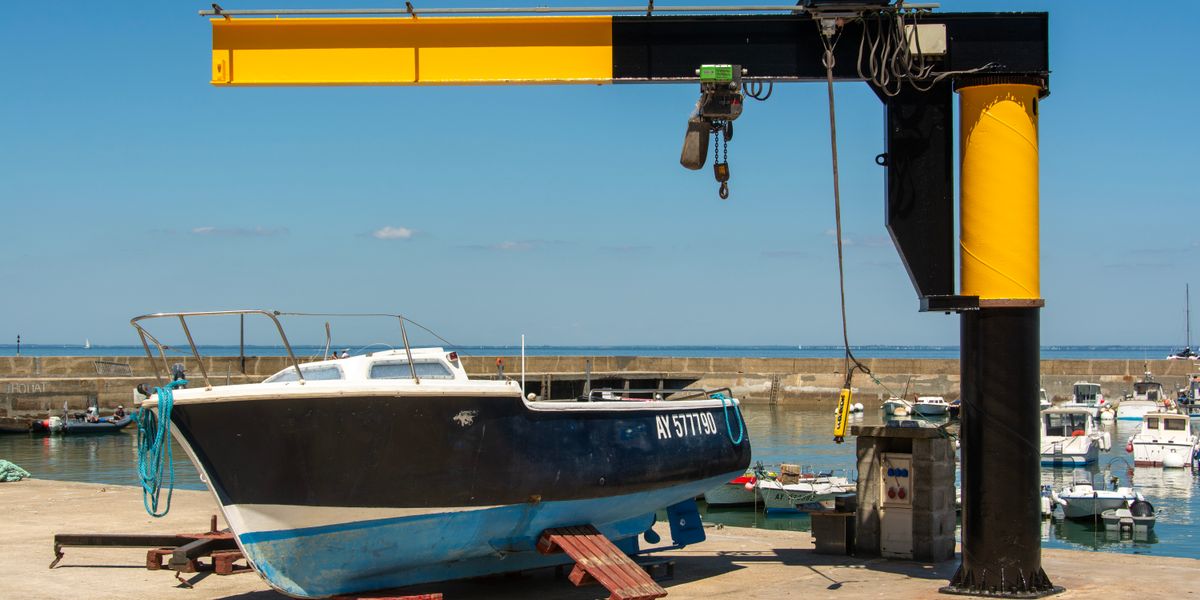 Grue de levage soulevant un bateau dans une marina