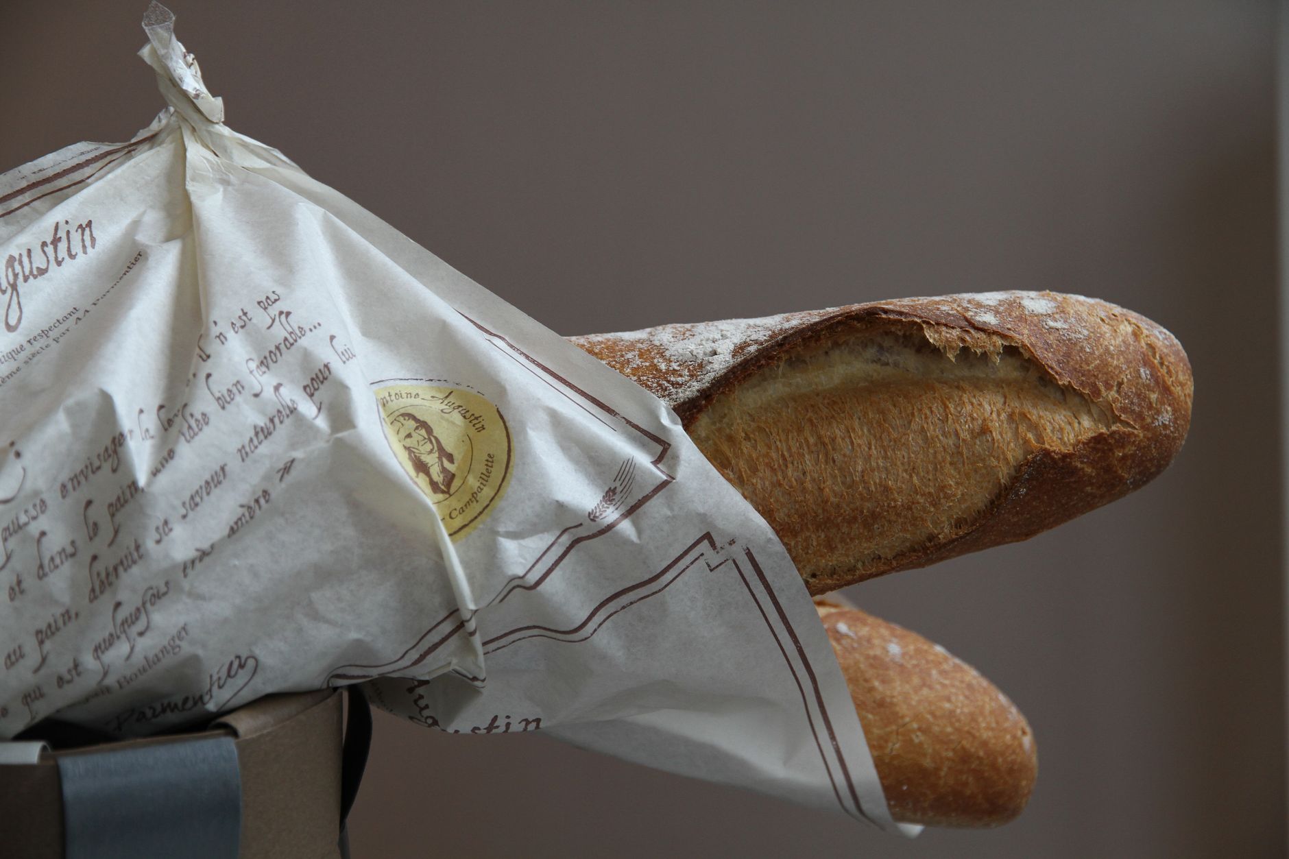 Crisp and golden French baguette wrapped in elegant paper packaging from a bakery.