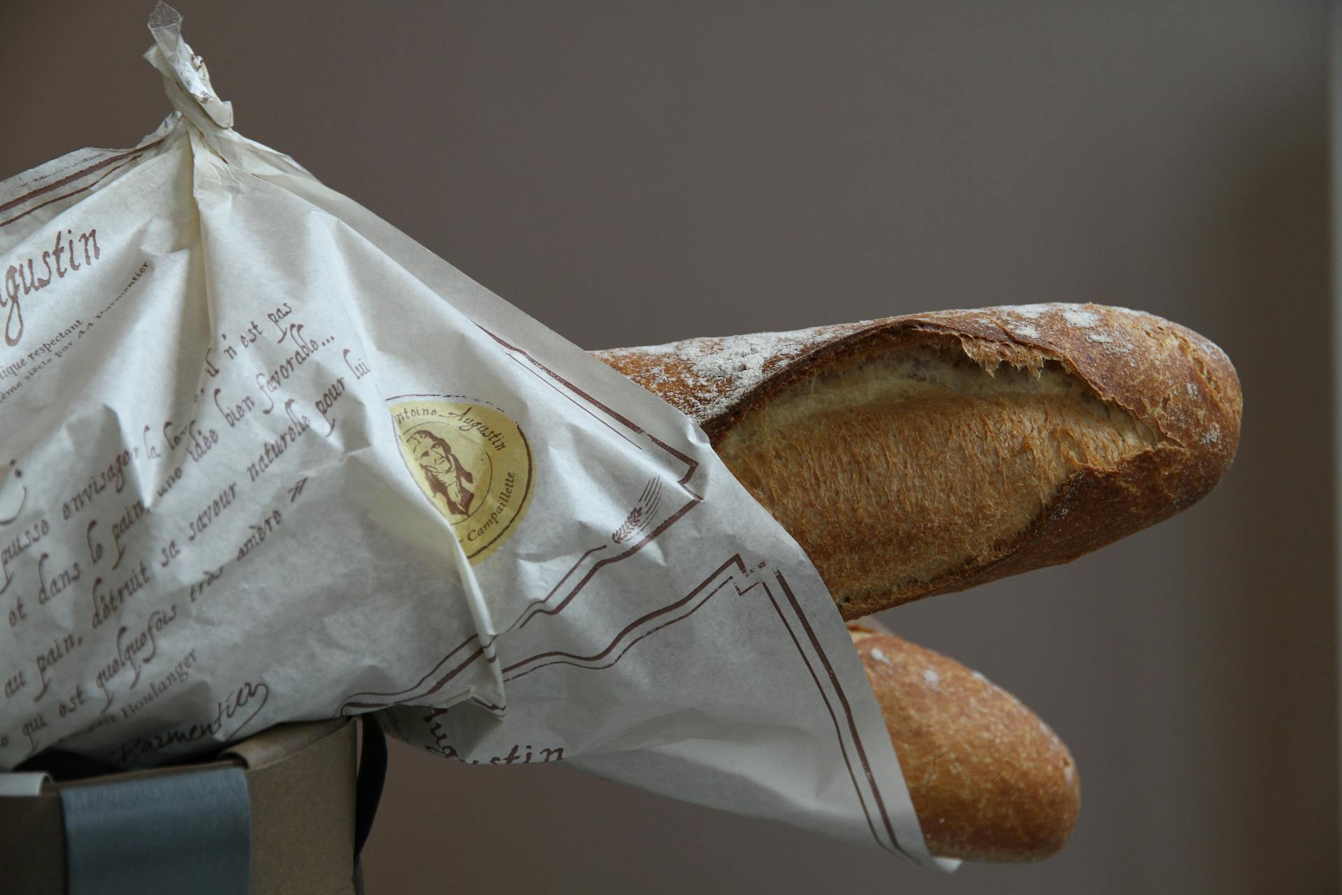 Crisp and golden French baguette wrapped in elegant paper packaging from a bakery.