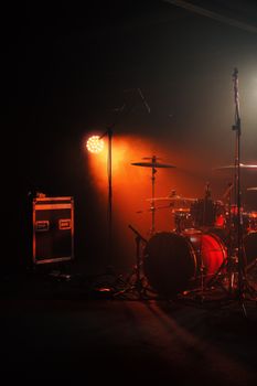 Atmospheric shot of a concert stage featuring drum set and warm lighting.