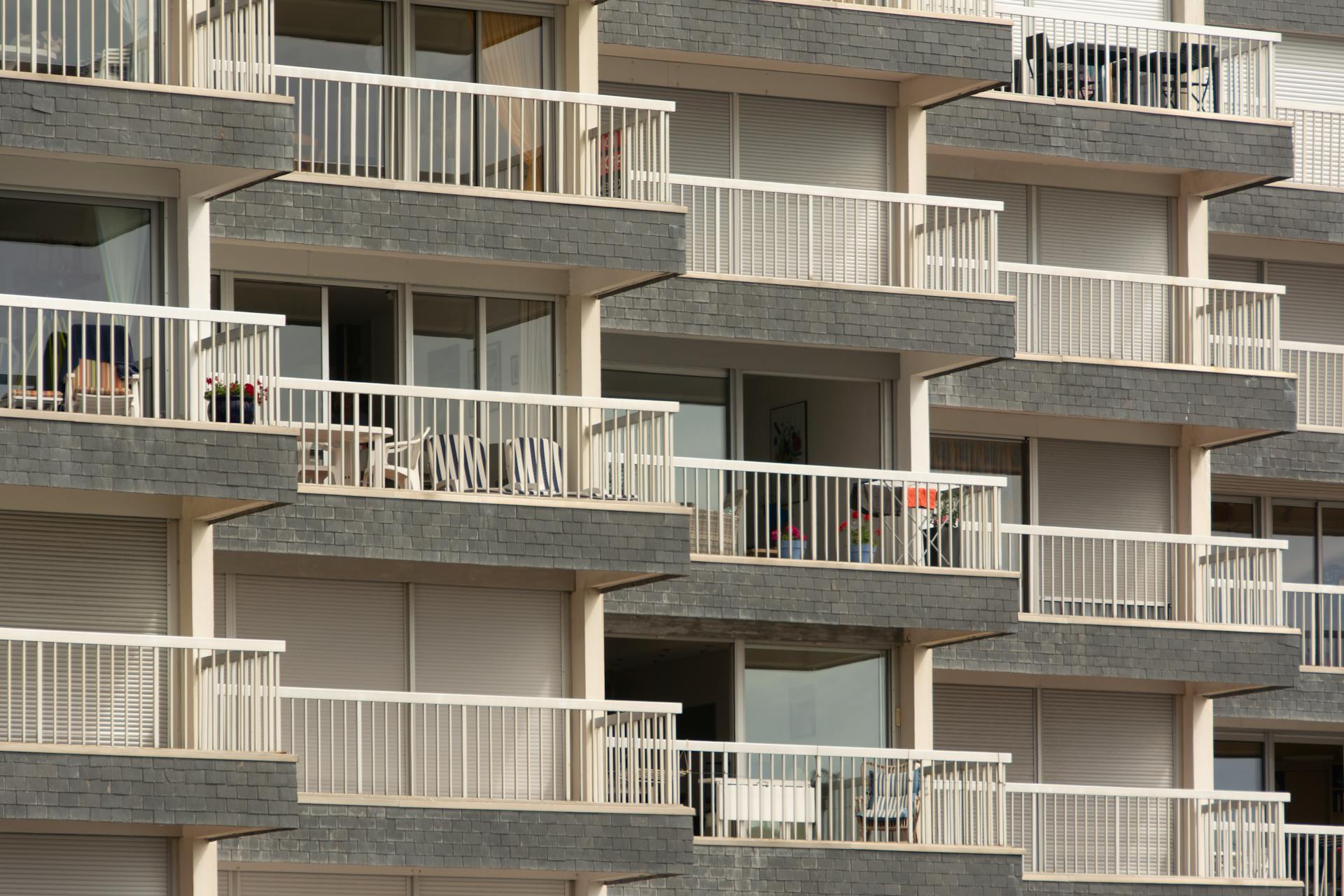 Modern apartment building facade with multiple balconies, showcasing urban architecture.