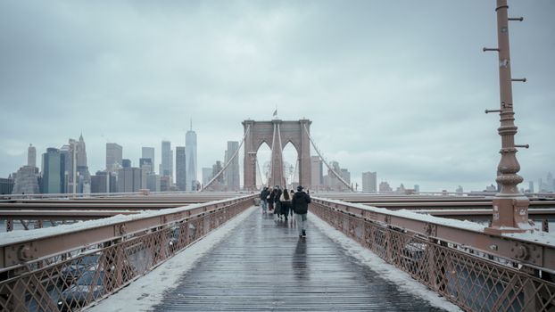 A snowy path on Brooklyn Bridge with the Manhattan skyline creating a wintery scenic view.