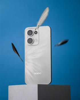 Silver smartphone with camera lenses, set against a blue backdrop with floating feathers.