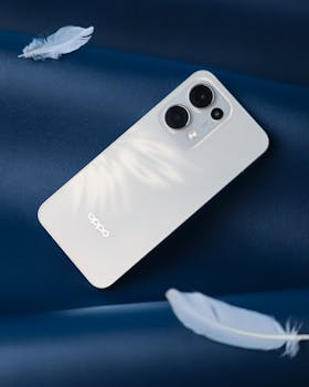 Elegant white smartphone with modern design placed on a smooth blue background.