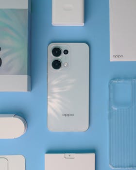 White smartphone with accessories on a blue surface. Minimalist composition.