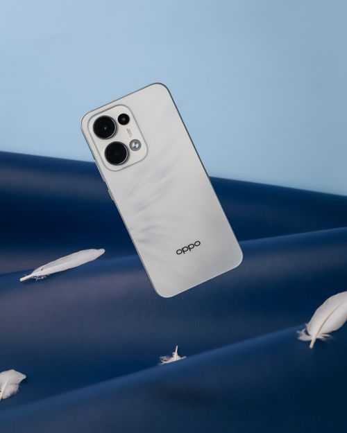 Free Stylish smartphone against a blue backdrop with floating feathers. Stock Photo