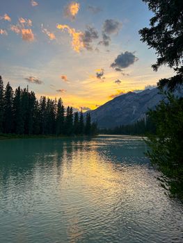 Breathtaking sunset at a tranquil lake in Banff, Alberta, with mountain and forest reflections.