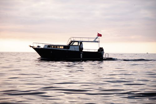 Free Elegant yacht with Turkish flag sailing at sunset on calm waters. Stock Photo