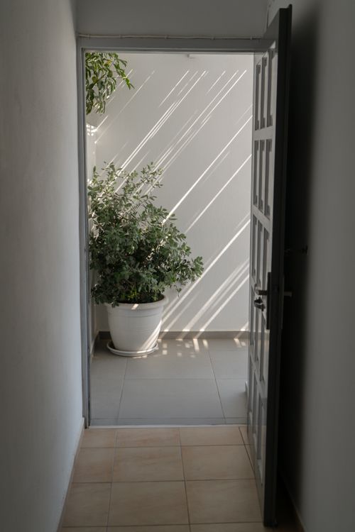 Free Open door revealing a peaceful atrium with potted plant in Fira, Greece. Stock Photo