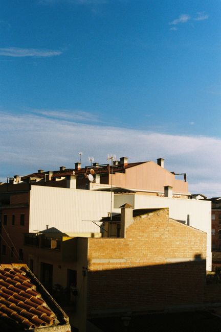 A serene view of urban rooftops under a clear blue sky, capturing warm afternoon light.