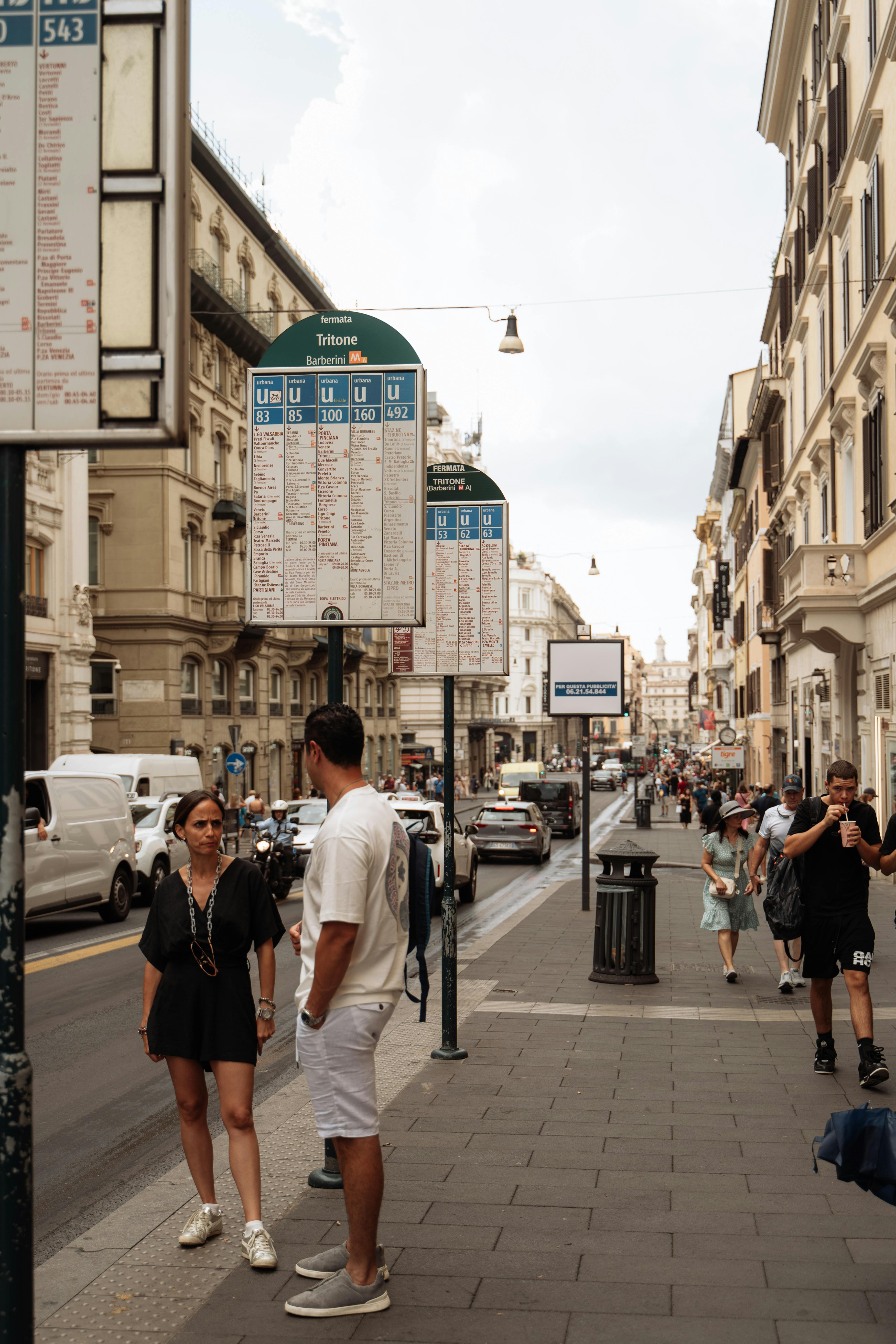 Pedestrians and traffic in a lively Rome street, capturing urban life and historic architecture.