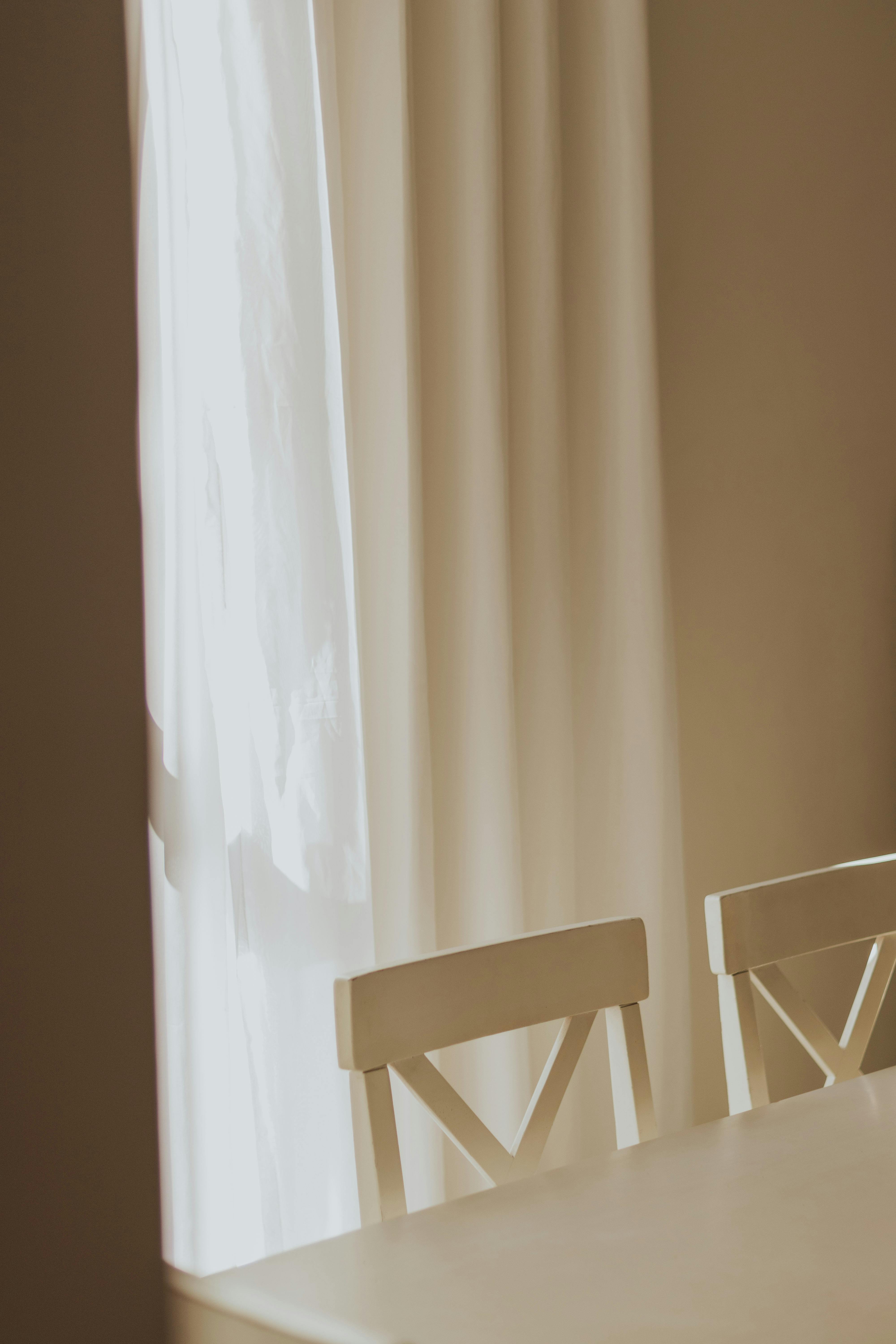 A cozy minimalist corner featuring white chairs bathed in soft sunlight.