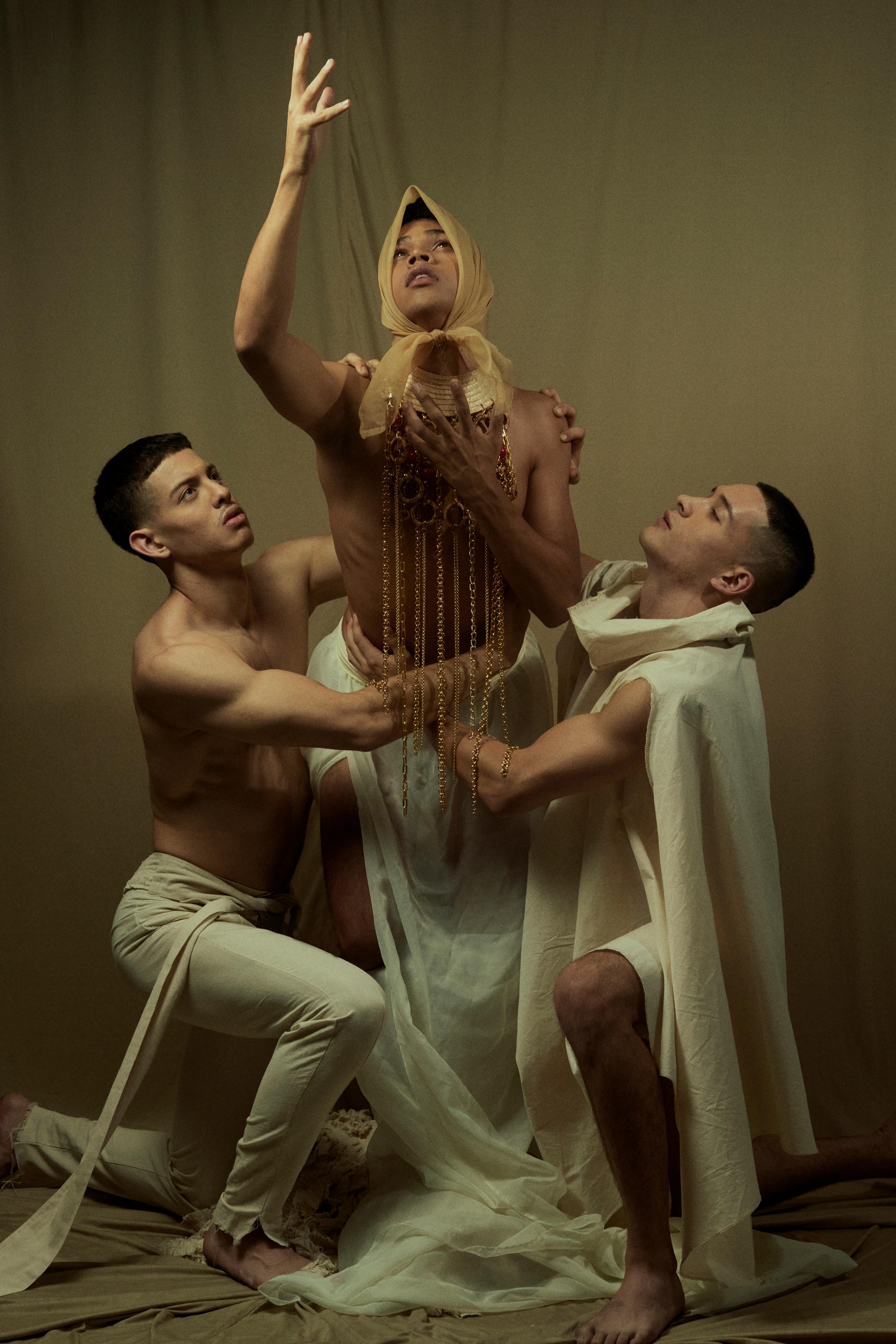 Gratuit Trois individus expriment une pose dramatique et artistique avec des tissus riches et des mouvements élégants. Photos