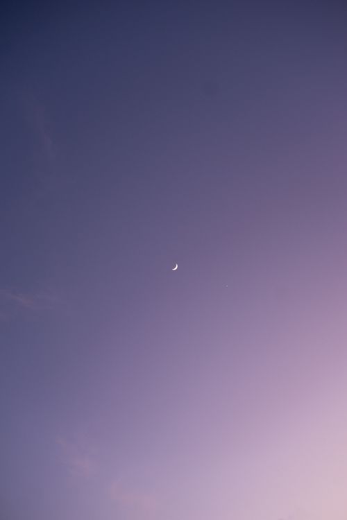 Free A serene crescent moon against a deep purple sky at twilight, perfect for peaceful and calming visuals. Stock Photo