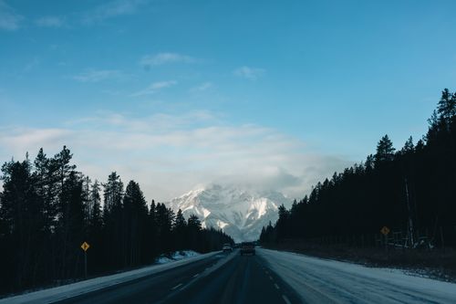 Free Winter road trip through Banff National Park with snow-covered mountains and pine trees. Stock Photo