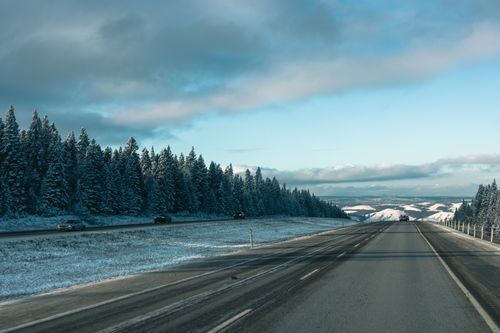 Free Capture of a snowy highway through Banff's scenic forested landscape, perfect for winter road trips. Stock Photo