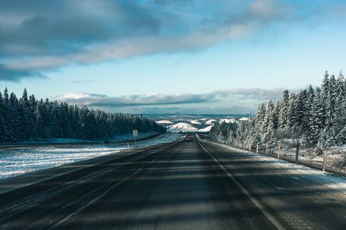 Free Captivating winter road view of Banff, Alberta, Canada with snow-dusted trees and mountains. Stock Photo