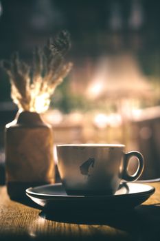 Warm scene of a coffee cup and vase in a softly lit room, creating a cozy ambiance.
