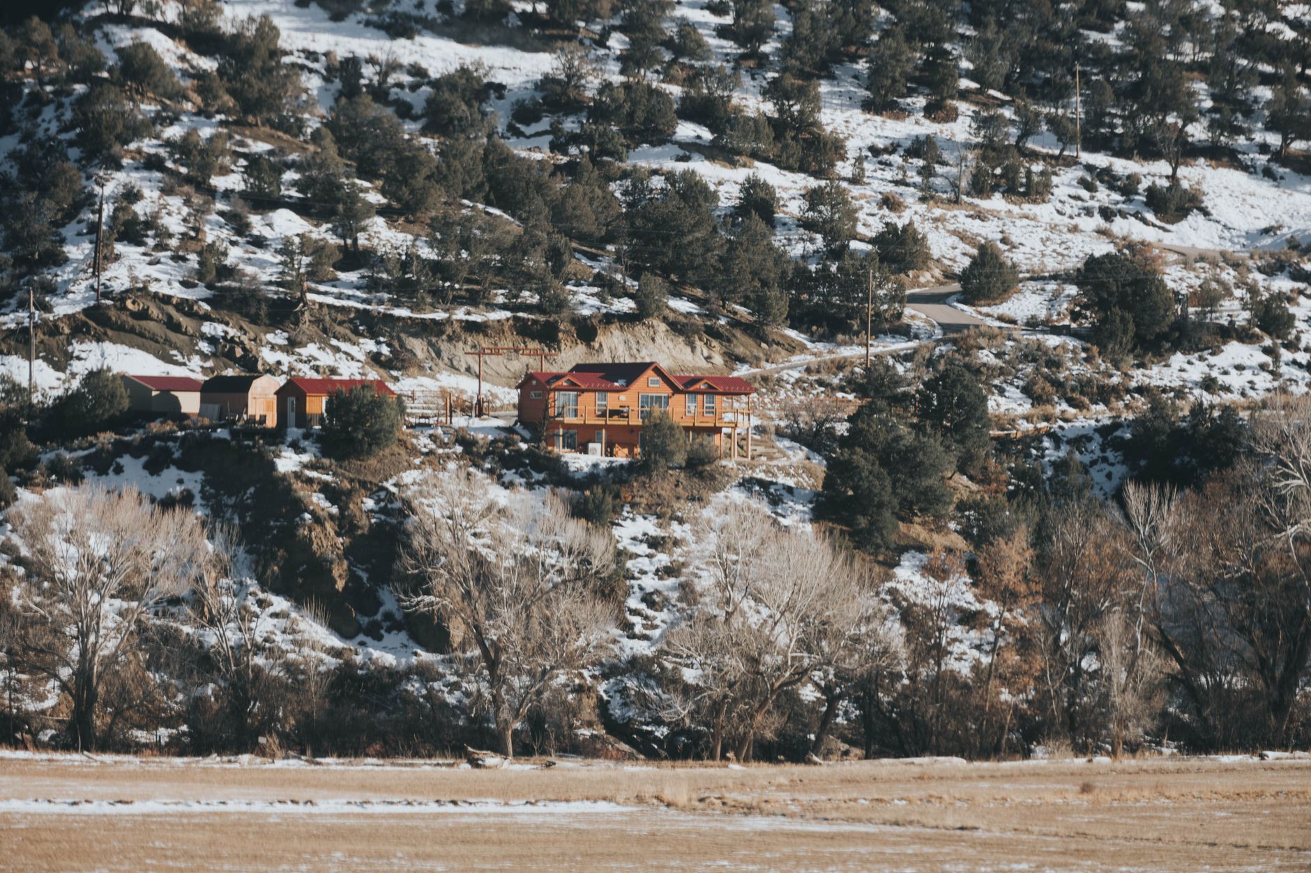 Idyllic winter cabin nestled among snowy mountains in Colorado landscape.
