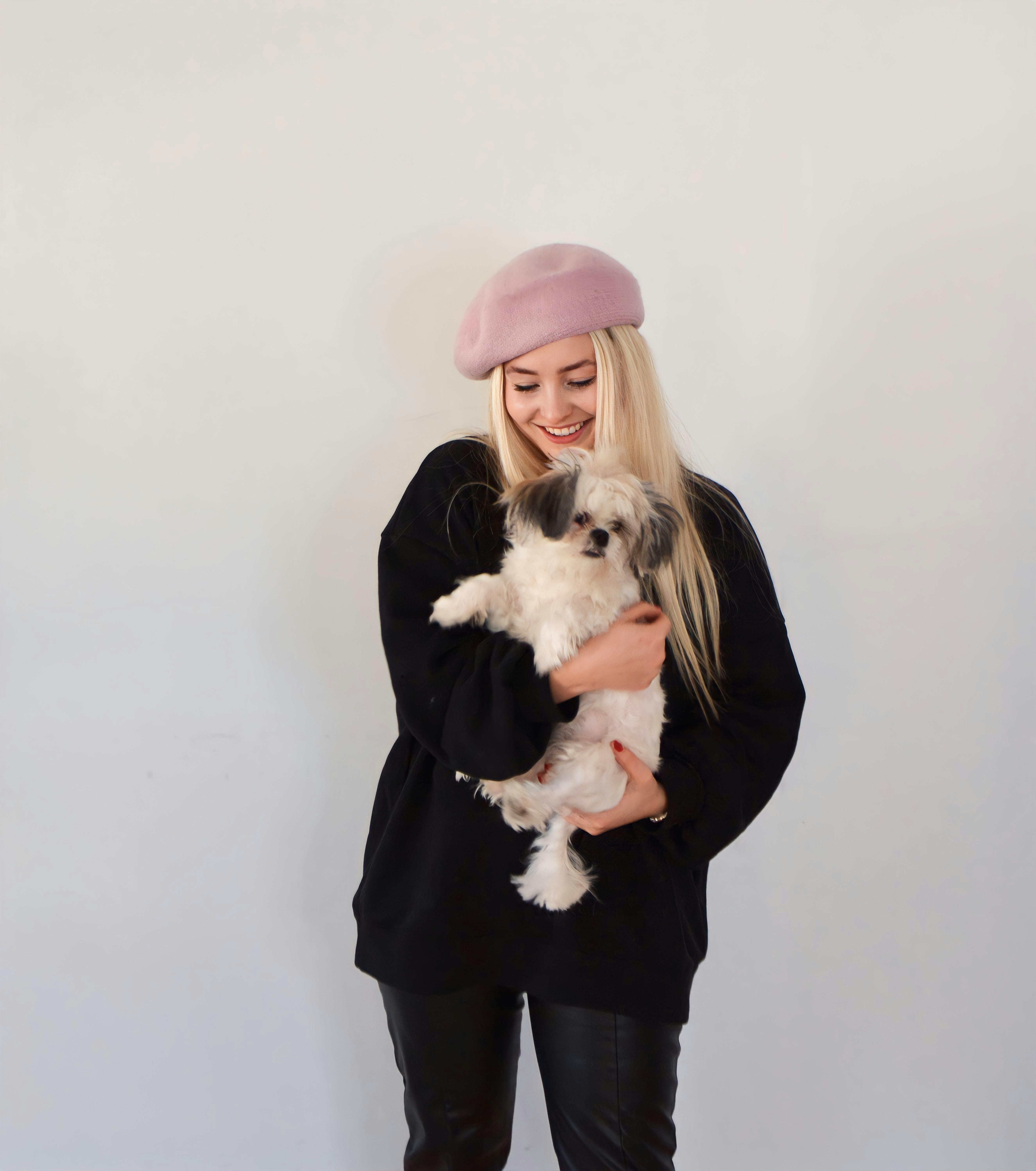 Happy young woman with a small fluffy dog in a cozy indoor setting.