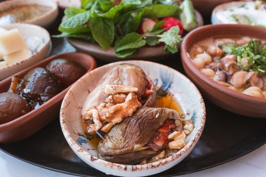 A variety of Middle Eastern dishes including stuffed eggplant, nuts, and fresh herbs on display.