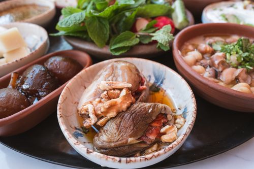 Free A variety of Middle Eastern dishes including stuffed eggplant, nuts, and fresh herbs on display. Stock Photo