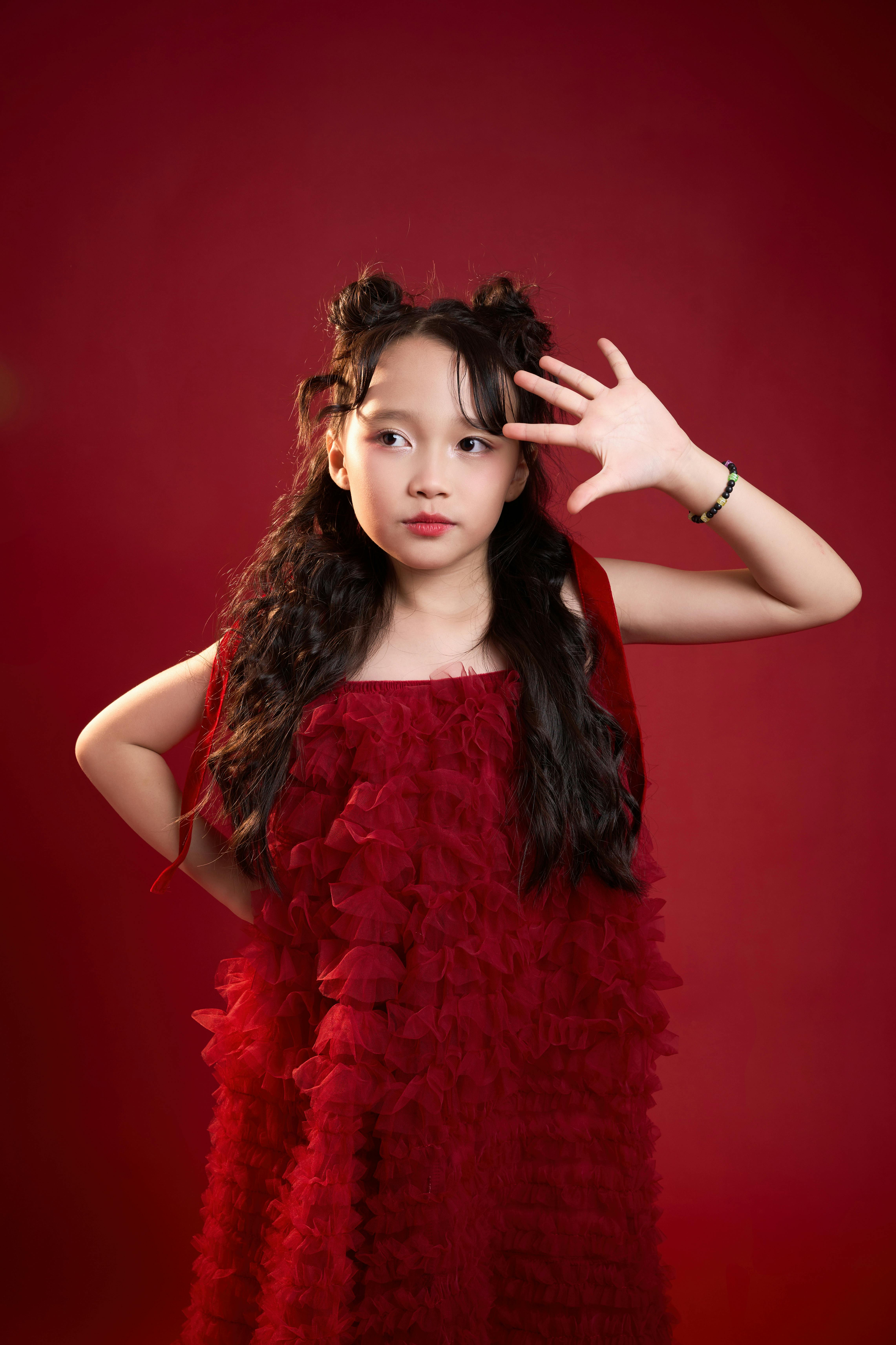 Gratis Linda chica con un vestido rojo posando sobre un fondo vívido, exudando encanto y confianza. Foto de stock