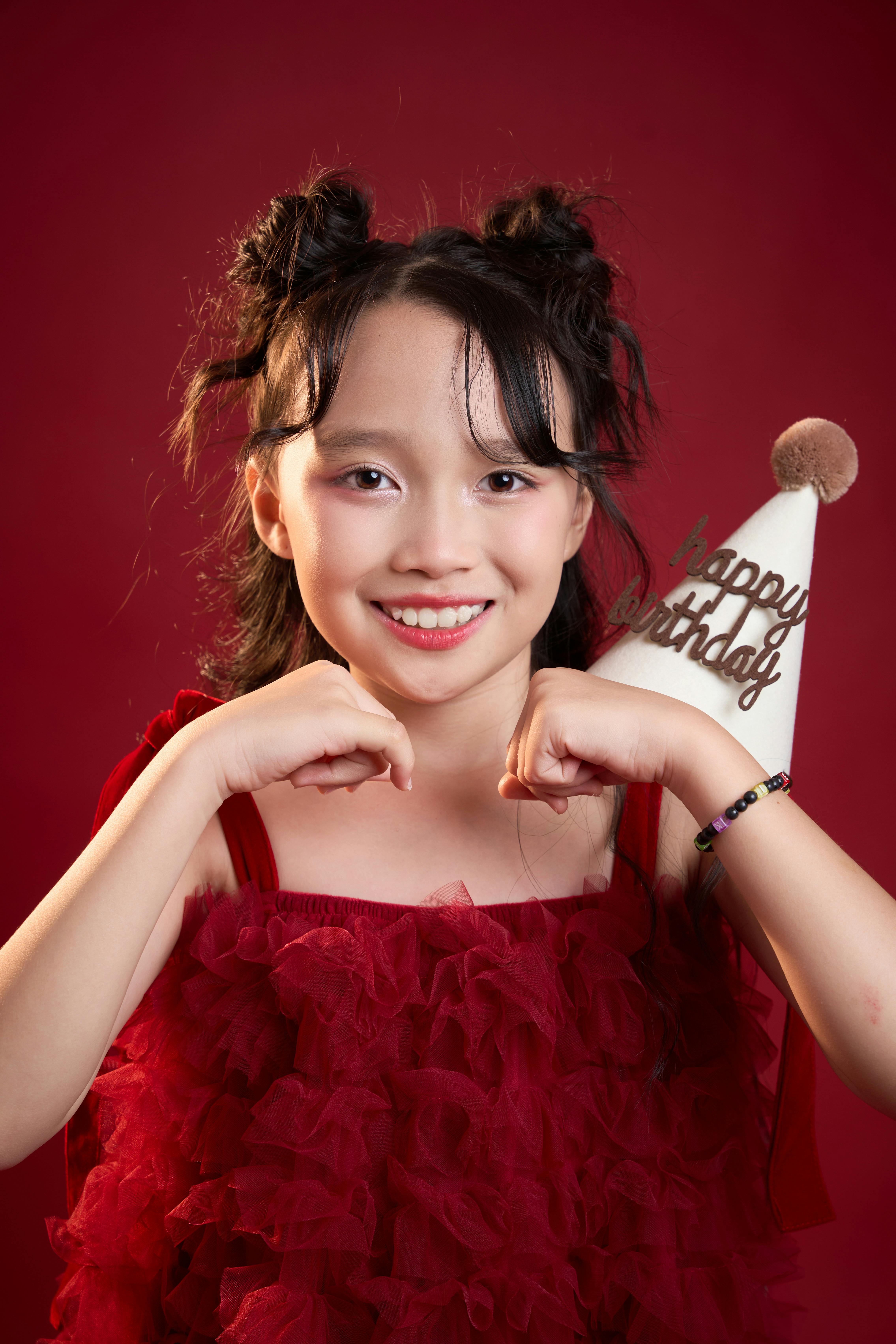 Joyful young girl in festive outfit holding a birthday hat.
