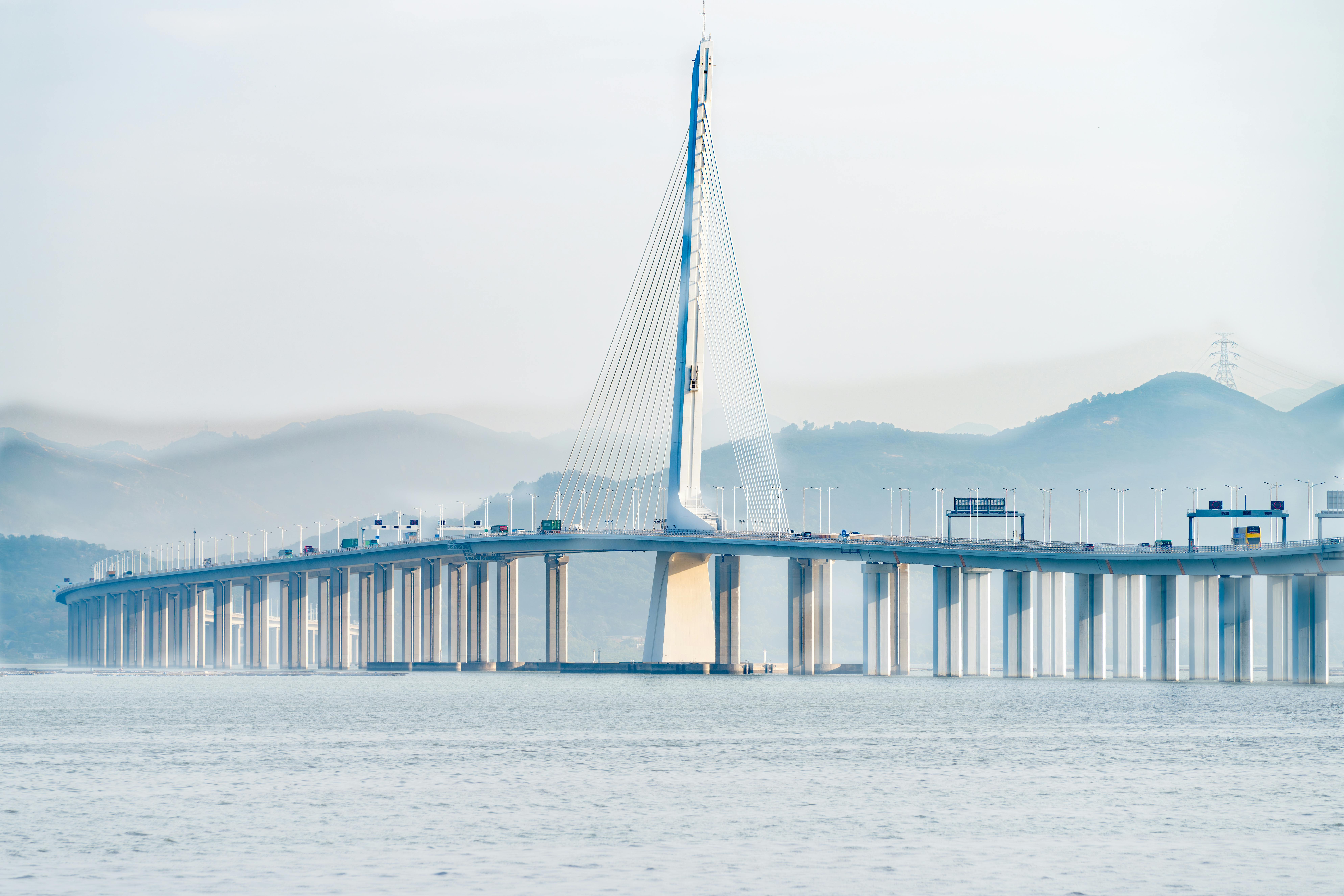 A magnificent cable-stayed bridge extending over calm waters with scenic mountains in the background
