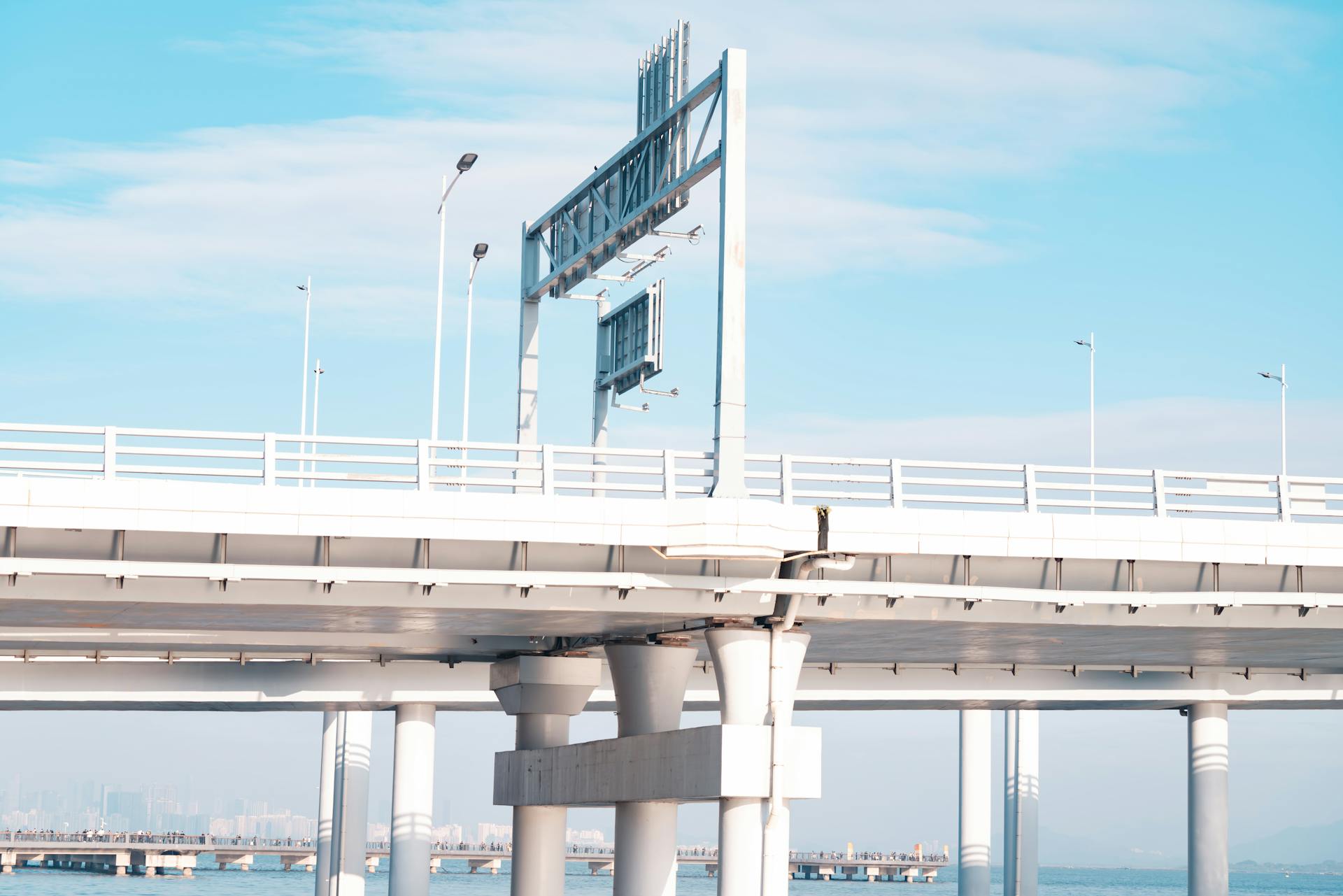 A modern coastal bridge with clear blue sky, featuring minimal traffic and urban skyline.