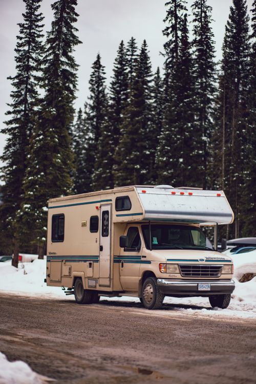 Free RV parked in a snowy forest setting, capturing a serene winter camping experience. Stock Photo
