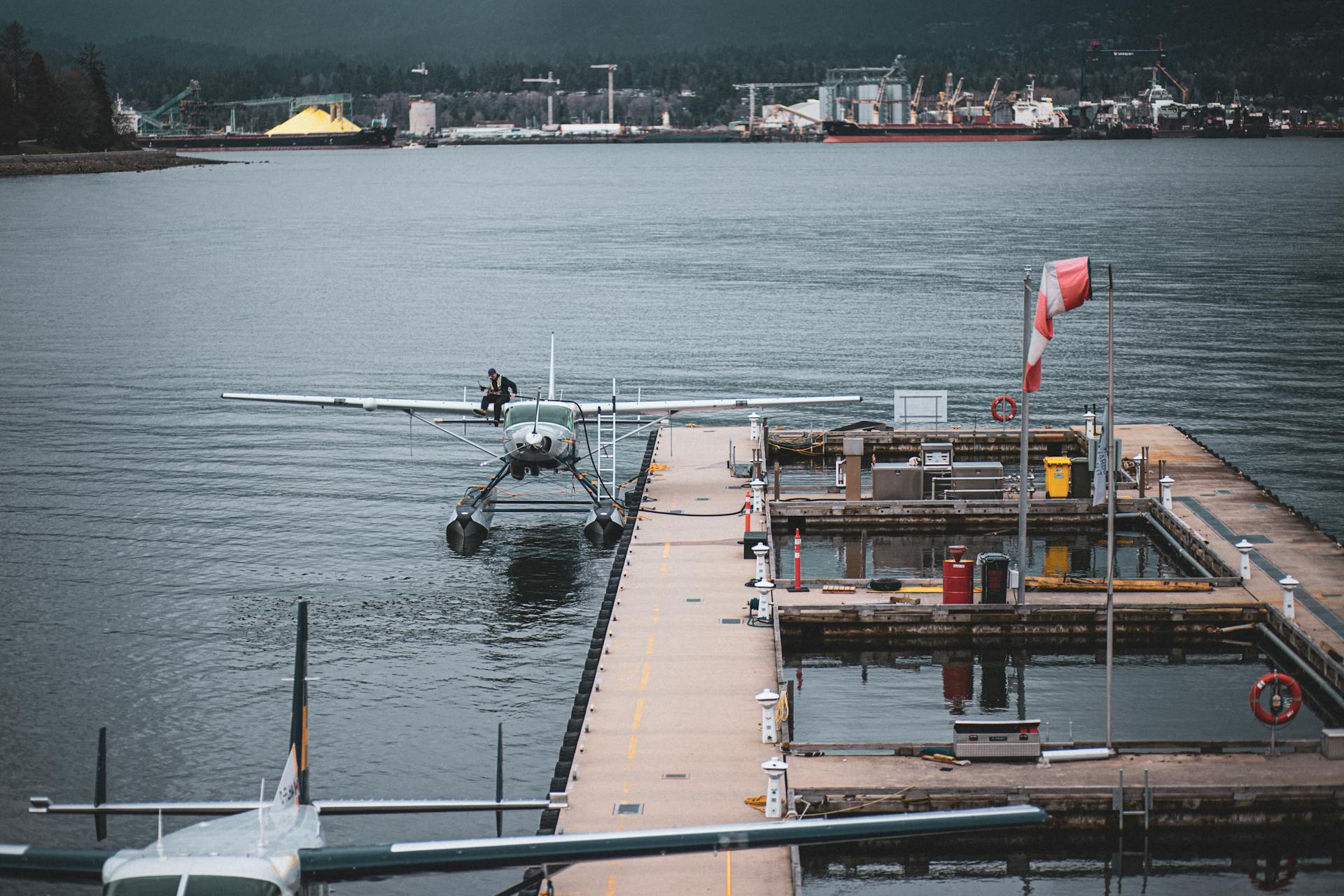 A picturesque view of a seaplane docked at Vancouver Harbour with cityscape in the background.