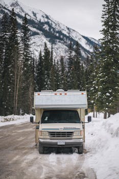 An RV parked in snowy Banff National Park with mountain backdrop.