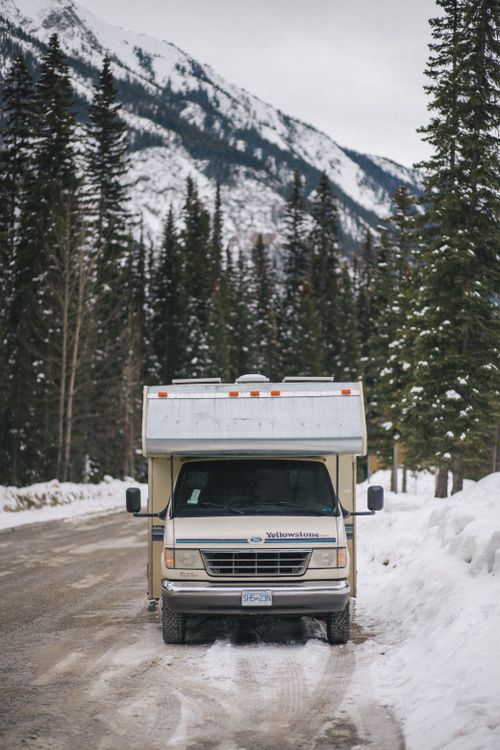 Free An RV parked in snowy Banff National Park with mountain backdrop. Stock Photo