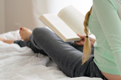 Free Woman Reading Book on Bed Stock Photo