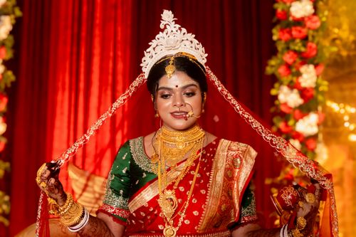 Free A beautiful Indian bride adorned in traditional red saree and elaborate gold jewelry during a wedding ceremony. Stock Photo